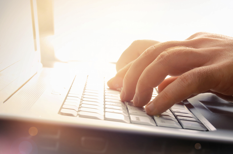 A person with their hands on the keyboard of a laptop