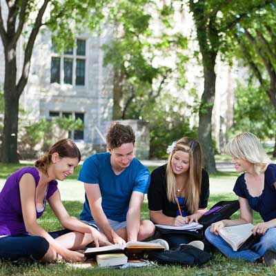 student sitting in the grass doing school work