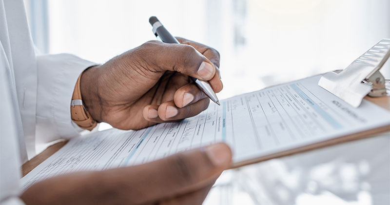 Doctor writing on clipboard