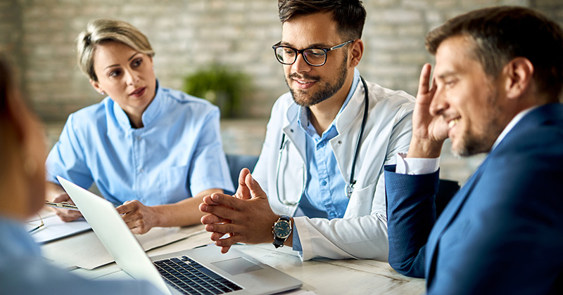 Team of doctors and admin using computer in meeting