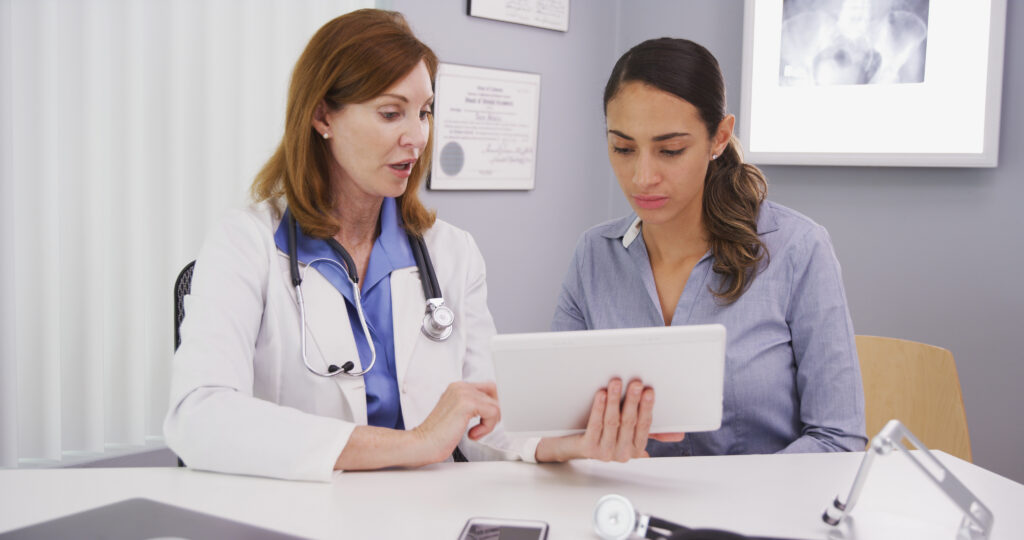 Senior medical physician using tablet to share lab results with young patient