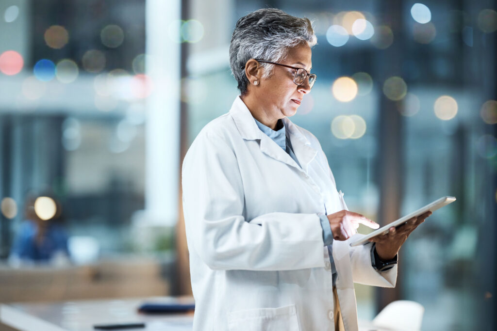 How DrChrono’s RCM Team Delivers Accuracy, Not Just Speed Hospital, tablet and senior doctor working online for medical report, planning and research in clinic. Technology, healthcare and woman with digital tech for telehealth, insurance and consultation.