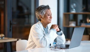 Doctor, laptop and senior woman in hospital working late or overtime on email, telehealth or research. Elderly, health and female medical physician reading healthcare information at night on computer.