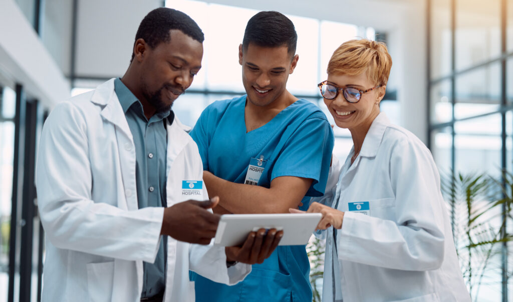 How DrChrono’s RCM Team Delivers Accuracy, Not Just Speed Doctor, team and tablet in healthcare planning for research, idea or meeting on technology at hospital. Happy group of doctors with touchscreen for medical data, collaboration or teamwork strategy.
