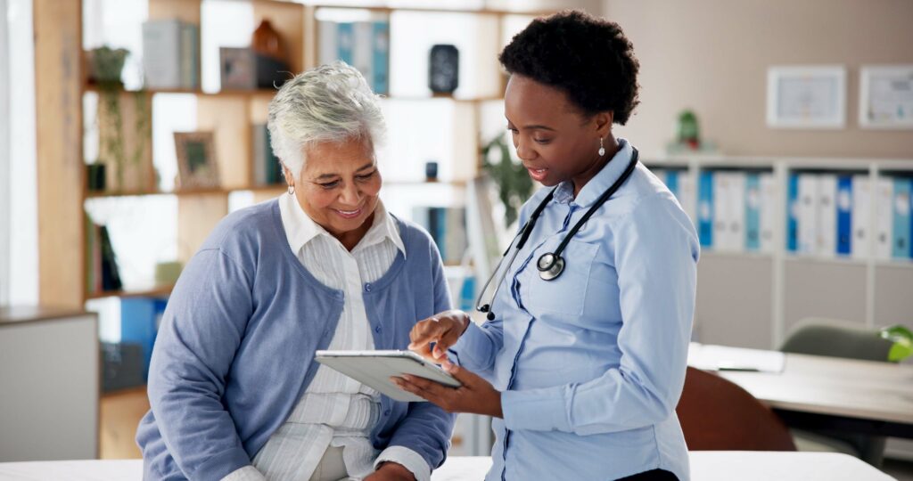 Senior woman, doctor and tablet with consultation, caregiver and care with digital results. Medical, communication and surgery talk for cardiology wellness with tech, help and nurse support in office.