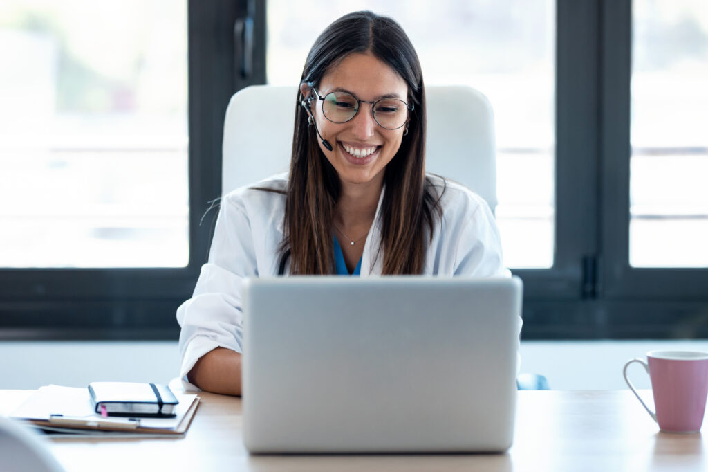 Shot of female doctor talking with colleagues through a video call with a laptop in the consultation.