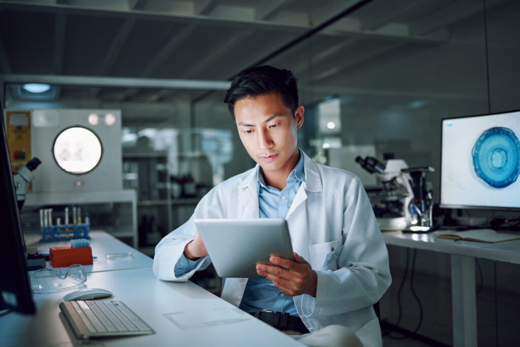 Tablet, planning and scientist with digital innovation, data and reading in laboratory. Asian man, doctor and information technology for futuristic medical research with pharma healthcare study.
