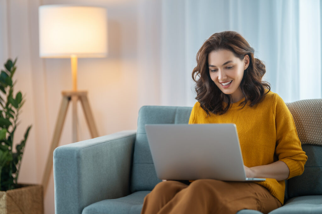 Happy casual beautiful woman using laptop at home.