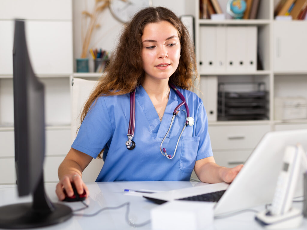 Young positive brunette female doctor with stethoscope working in medical office