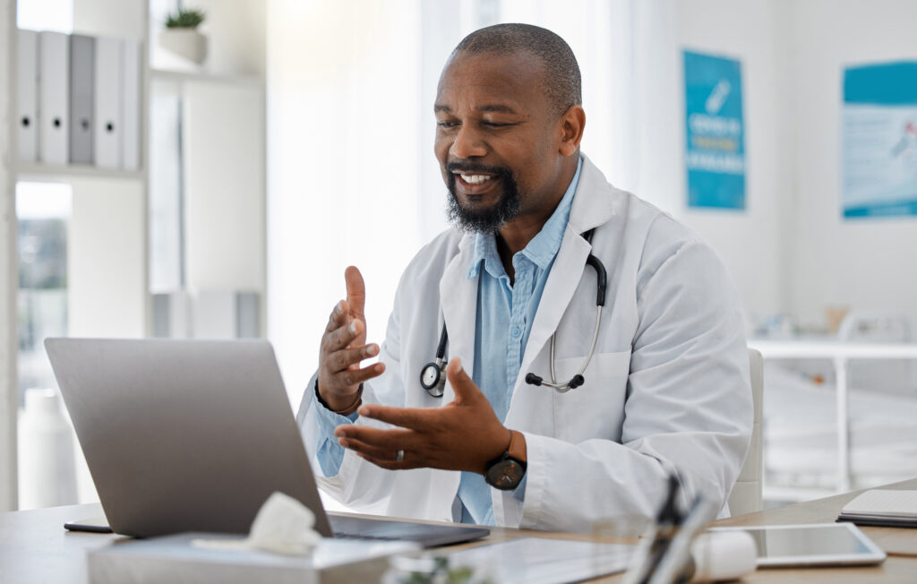 Telemedicine, healthcare and video call with doctor talking on laptop to online patient during a consultation. Happy black professional offering support or medical advice during a medical appointment.