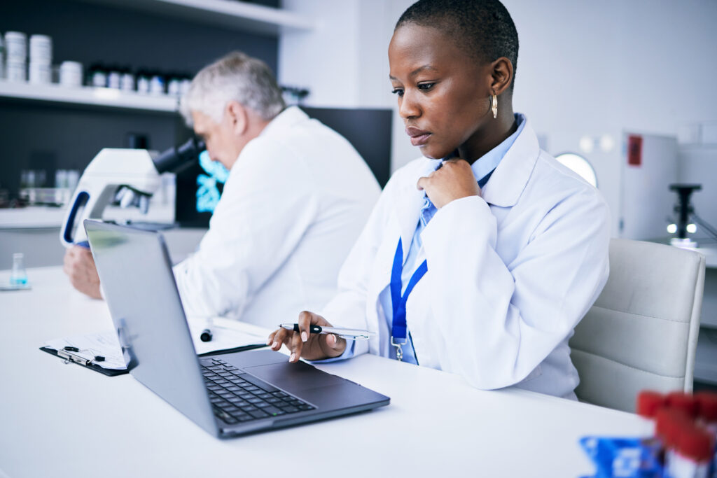 Laptop, science and woman in a laboratory for research, internet or medical results. Serious person and a man scientist or doctor team with tech for scientific innovation, planning or data report.