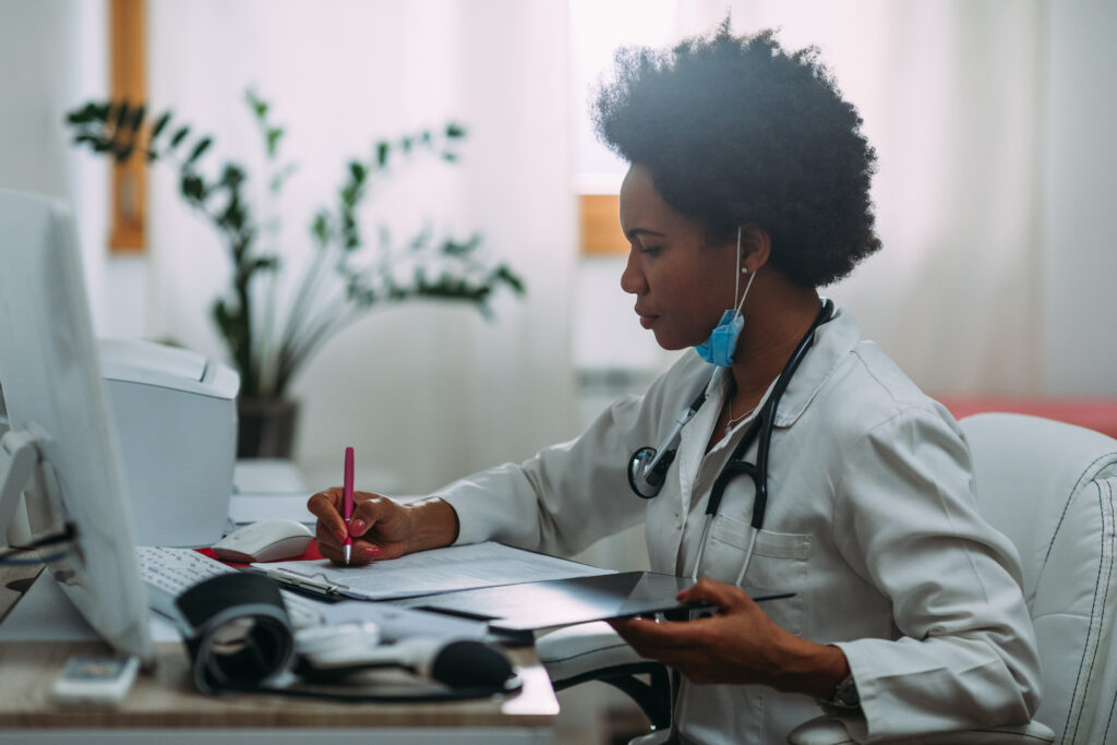 Hardworking african american doctor writing diagnosis in doctor's office.