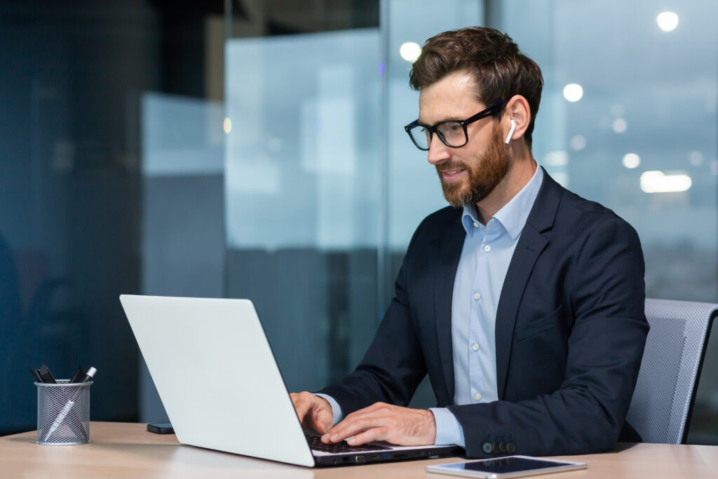 How AI Scribe Software Supports Smarter CPT and HCPCS Coding Successful mature businessman at work with laptop inside office, man in business suit sitting at desk typing on computer, satisfied with achievement result and work.