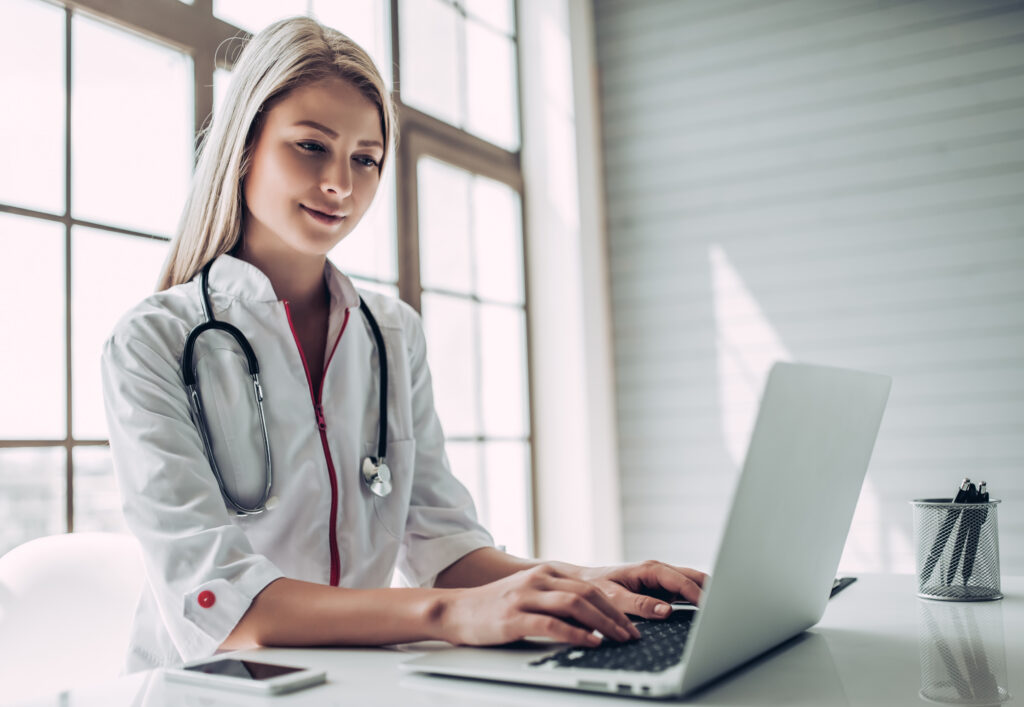 How to Know When It's Time to Switch EHR Systems Attractive young female doctor is working with laptop in light cabinet.