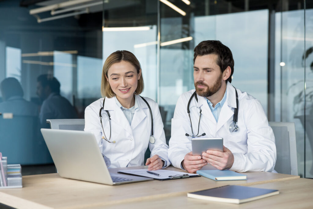 Doctors reviewing patient data and health records, using modern technology for efficient healthcare management and professional medical consultation in a clinic setting