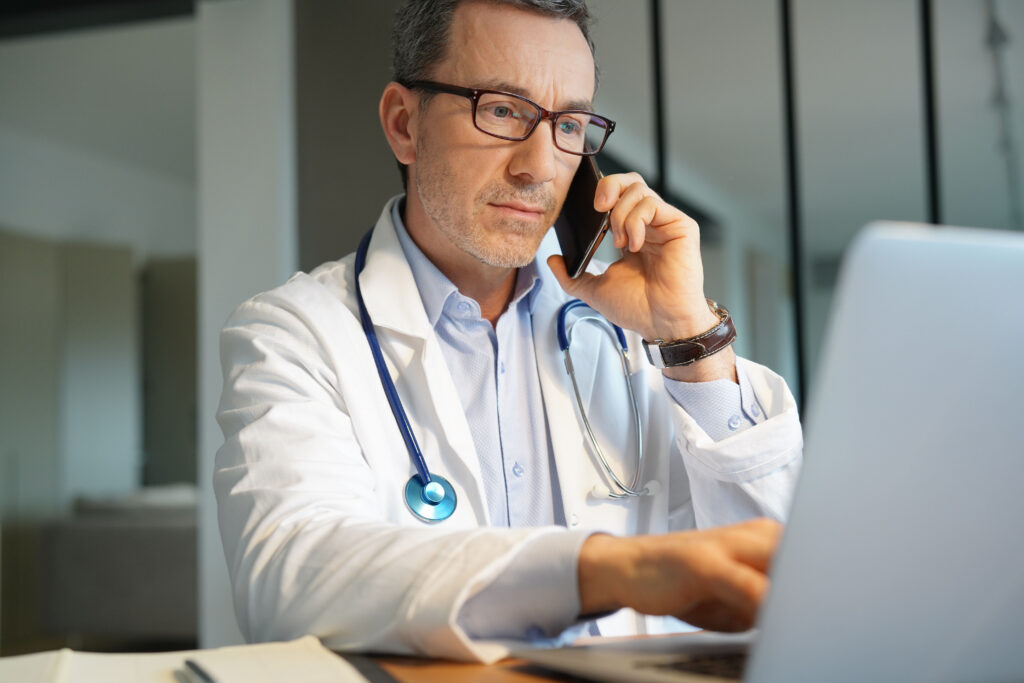 How to Know When It's Time to Switch EHR Systems Doctor in office working on laptop talking on phone