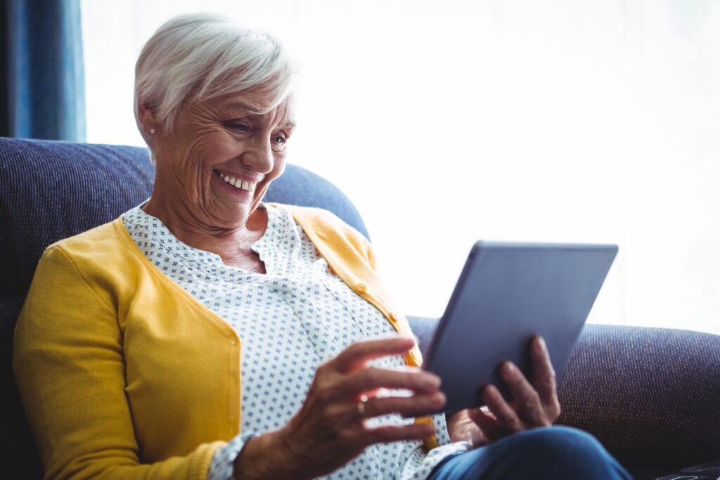 How a Modern Patient Portal Improves Engagement and Cuts Admin Work Smiling senior woman looking and laughing at her digital tablet