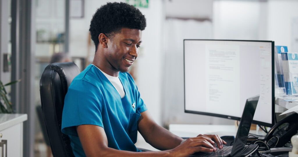 How a Modern Patient Portal Improves Engagement and Cuts Admin Work Black man, nurse and typing with laptop for online booking, administration or medical appointment. African person, smile and health admin with computer at front desk for planning visit or schedule.