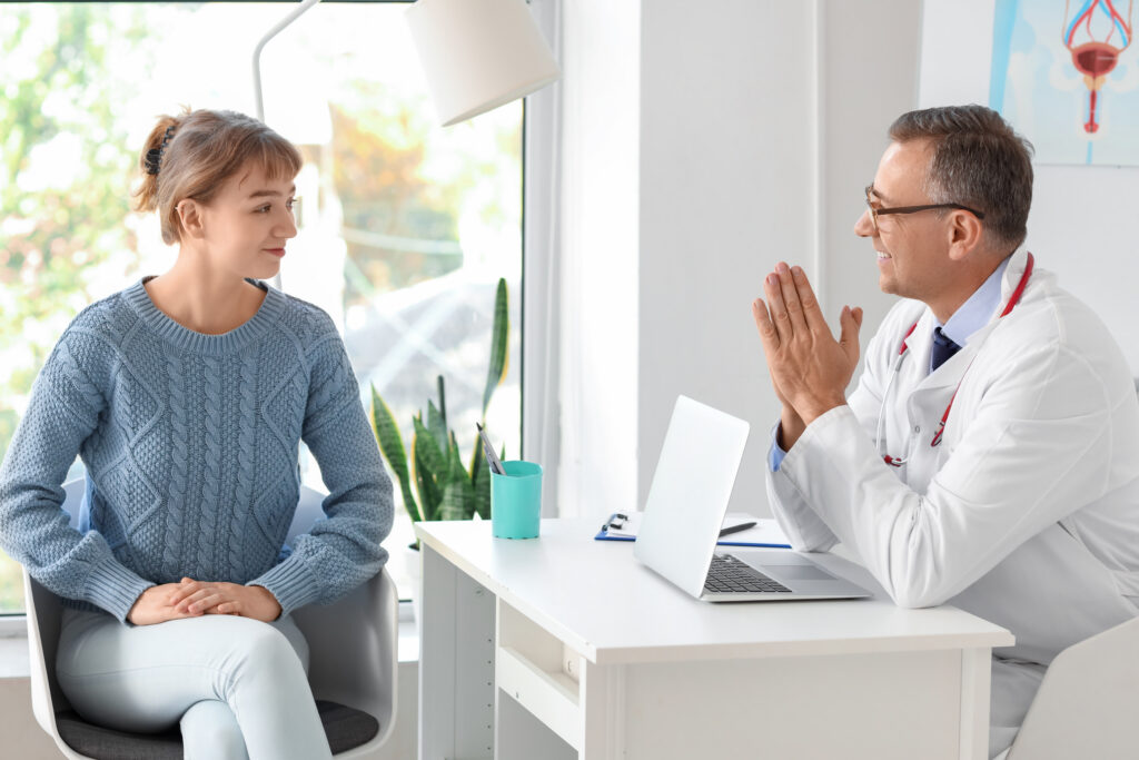 Mature doctor working with patient at desk in medical office